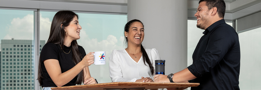 Three office workers chat over coffee