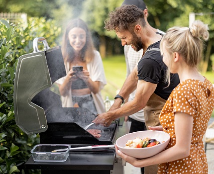 Group of friends grilling meat on barbecue