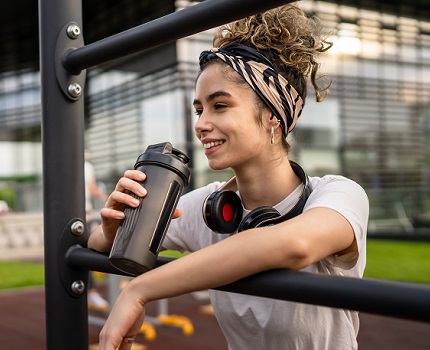 Girl drinking protein shake at outdoor gym