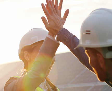 two workers in hard hats high five each other