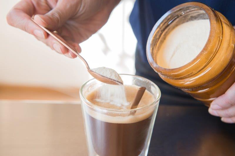 Monique dropping powdered milk into a cup of coffee