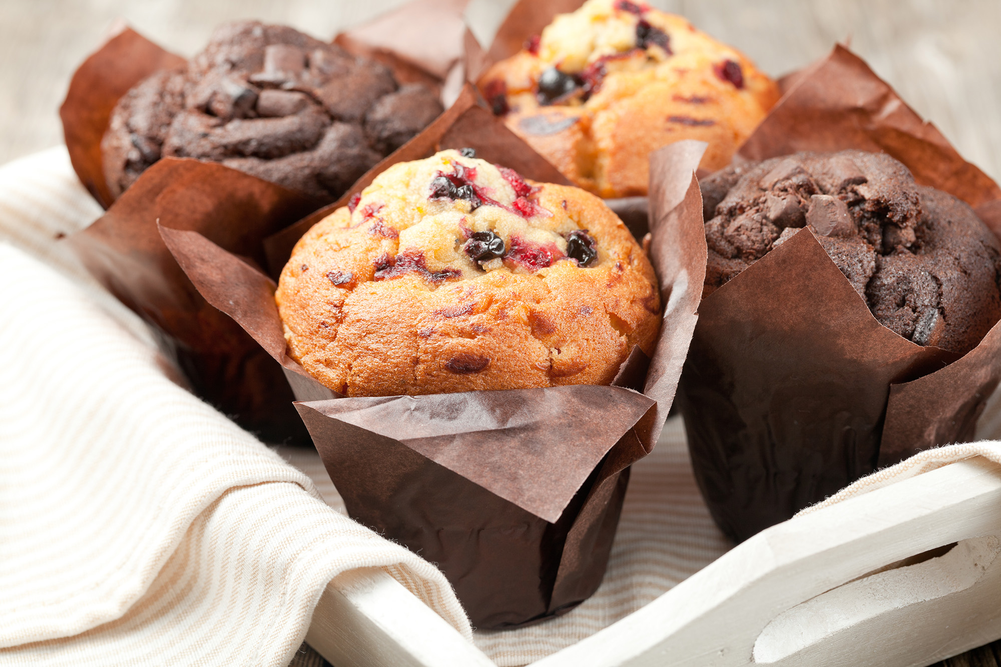Chocolate and Blueberry muffins rest comfortably on a cloth lined tray. 