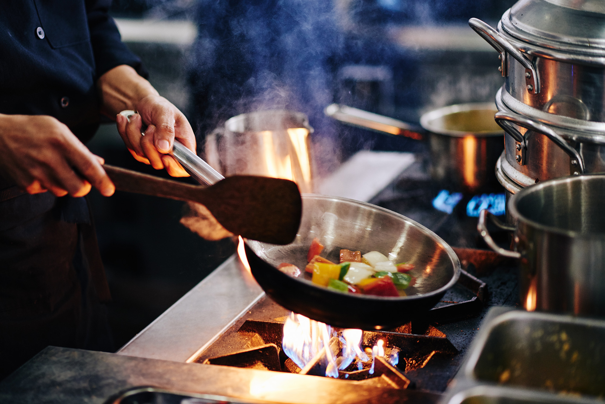 Close up of a chef frying vegetables over the stove
