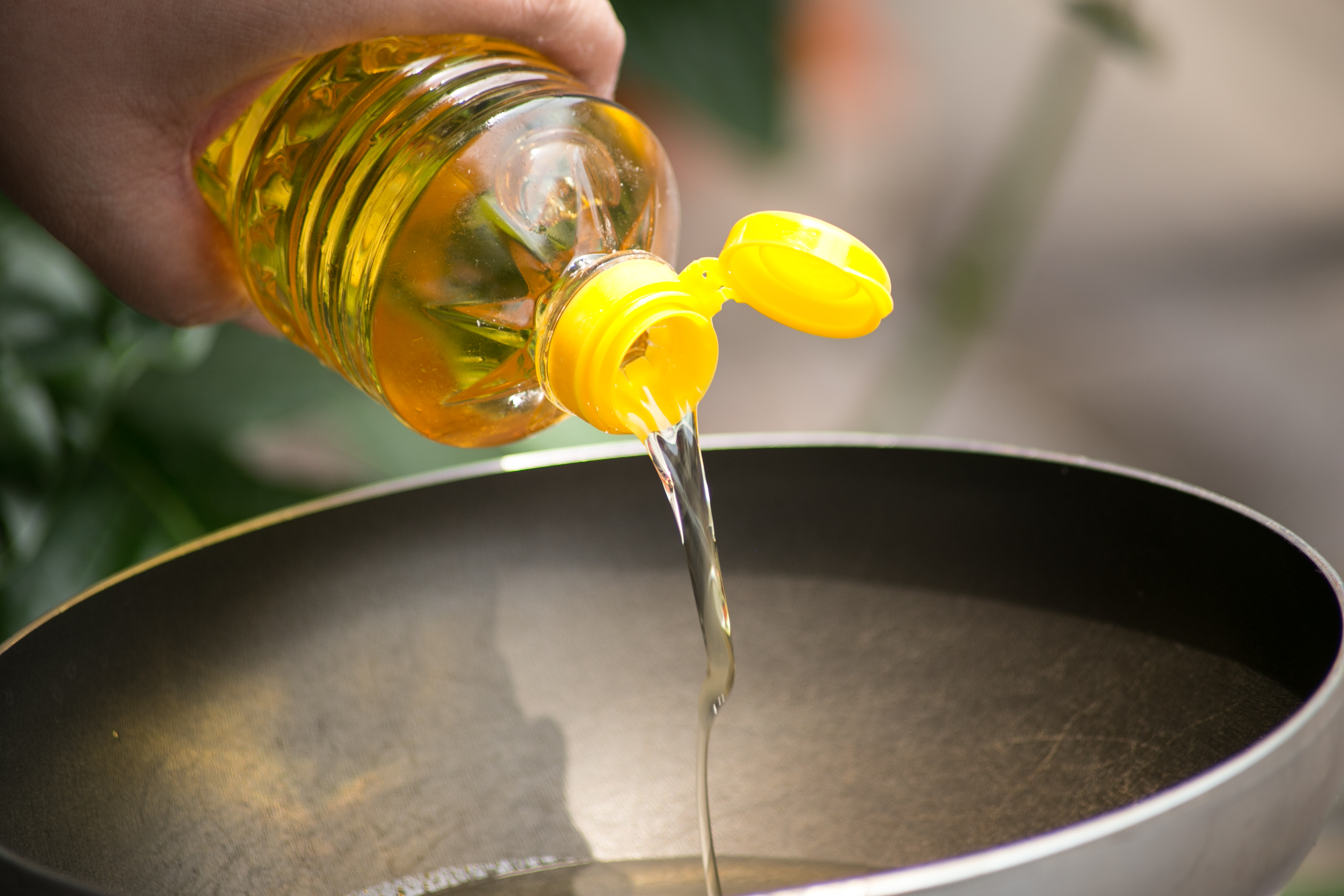 Bottled oil being poured in a pan