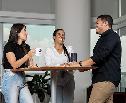 Three office workers chat over coffee