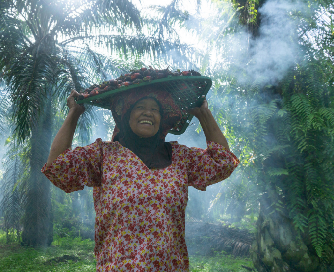 Smiling worker carrying palm seeds