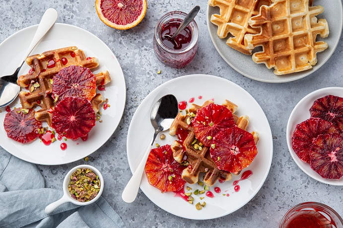 Plates with waffles, jam and fruit